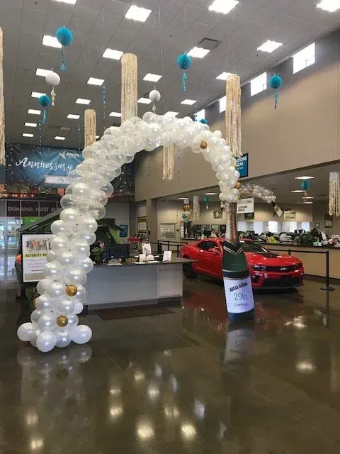 A balloon arch in a store with a red car in the background