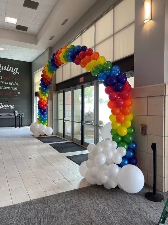 A rainbow colored balloon arch in a building