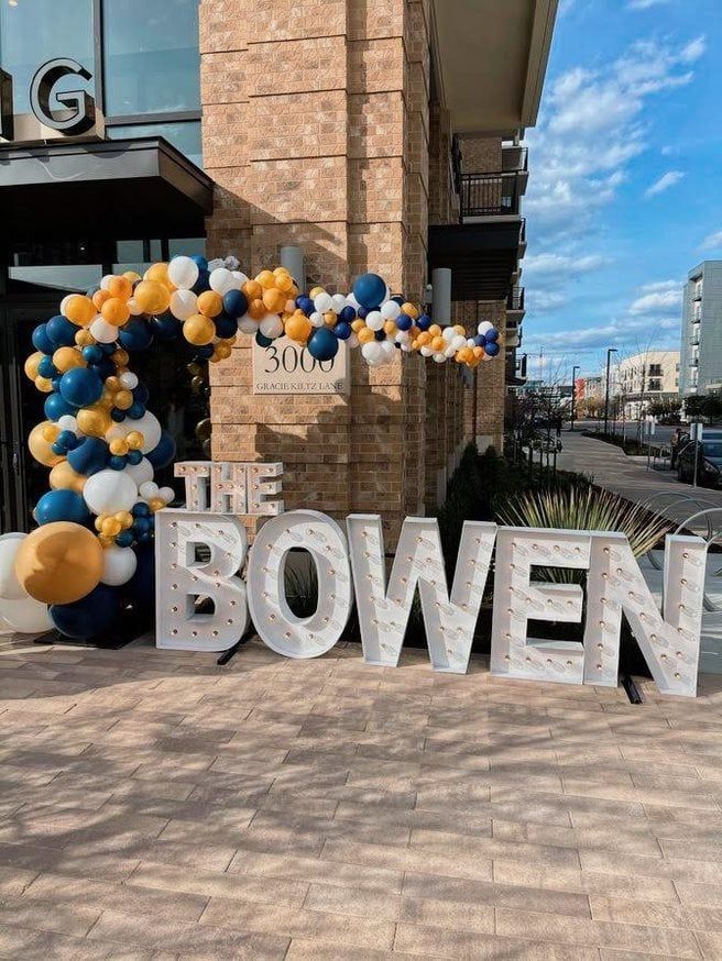 A large sign that says the bowen is in front of a building with balloons.