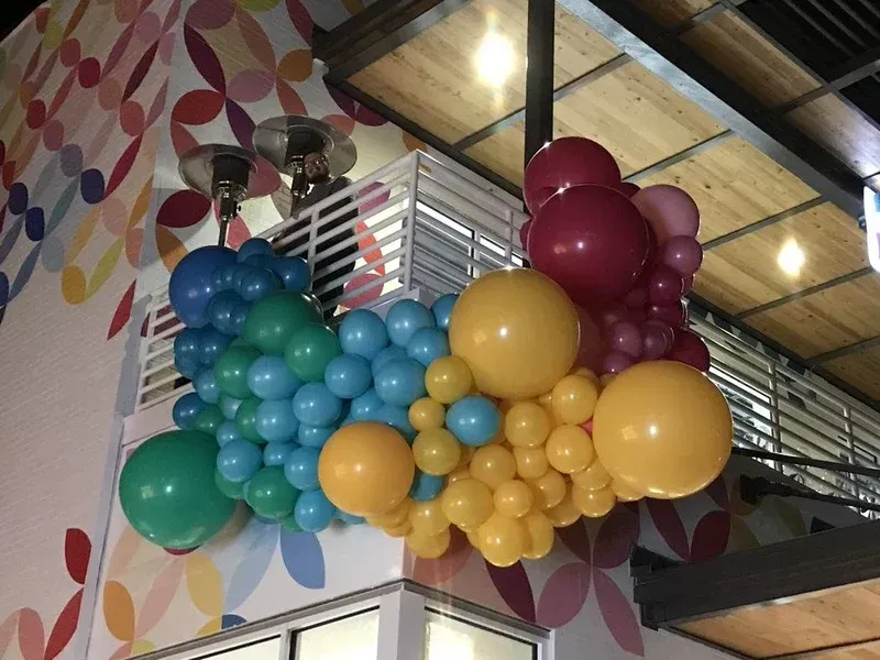 A bunch of balloons are hanging from the ceiling of a building.