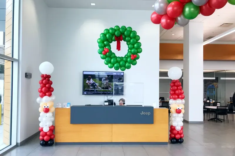 A dealership is decorated for christmas with balloons and a wreath on the wall.