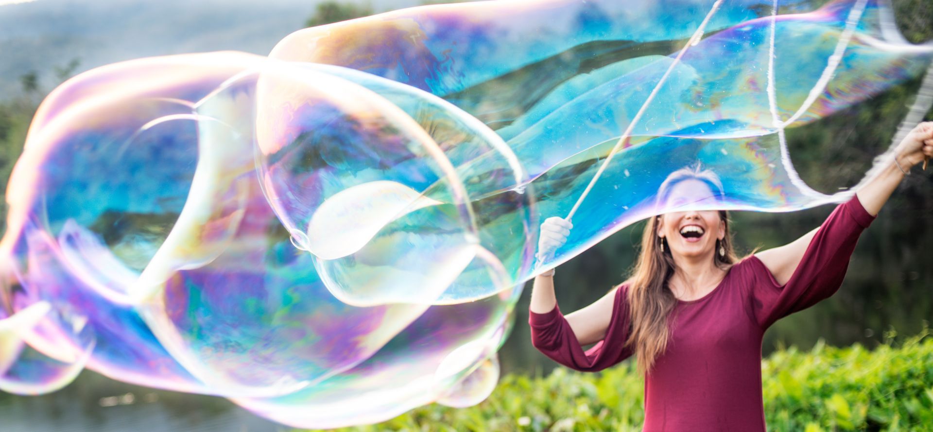 A woman is holding a giant soap bubble in front of her face.