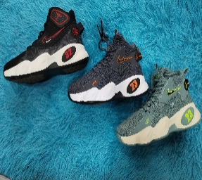 Tres zapatillas de baloncesto de caña alta: negra, gris y verde azulado, cada una con "23" y el logotipo de Nike sobre una superficie difusa azul.