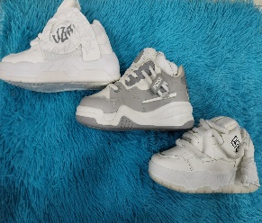 Tres zapatillas blancas y grises sobre una superficie azul peluda.