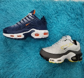 Dos zapatillas Nike sobre una superficie azul esponjosa; una azul marino y naranja, la otra blanca y amarilla.