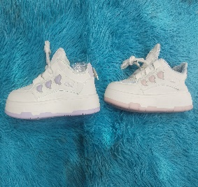 Zapatillas blancas y lavanda con detalles de corazón sobre una superficie difusa azul.