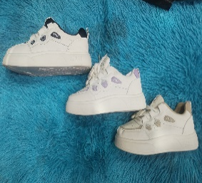 Tres zapatillas blancas con suela gruesa sobre una superficie texturizada azul.