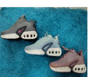 Tres zapatillas en gris, azul y malva sobre una superficie azul esponjosa.