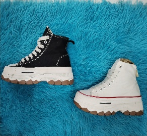 Zapatillas de plataforma en blanco y negro sobre una superficie azul esponjosa.
