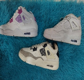 Tres pares de zapatillas Air Jordan blancas y de colores sobre una alfombra peluda azul.