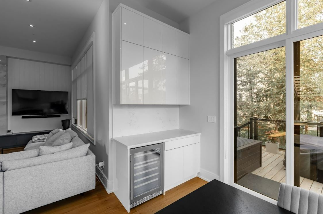 Modern living area with a white sofa, wall-mounted TV, and a small kitchenette