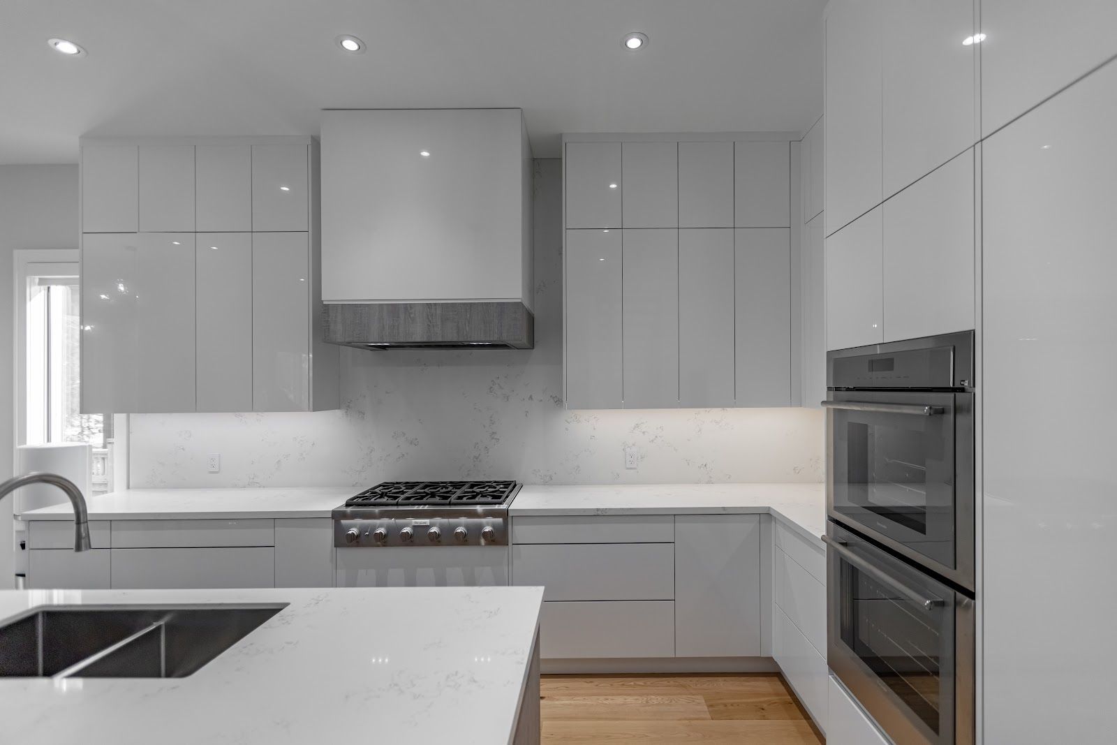 A kitchen with white cabinets , stainless steel appliances , a sink , and a stove.
