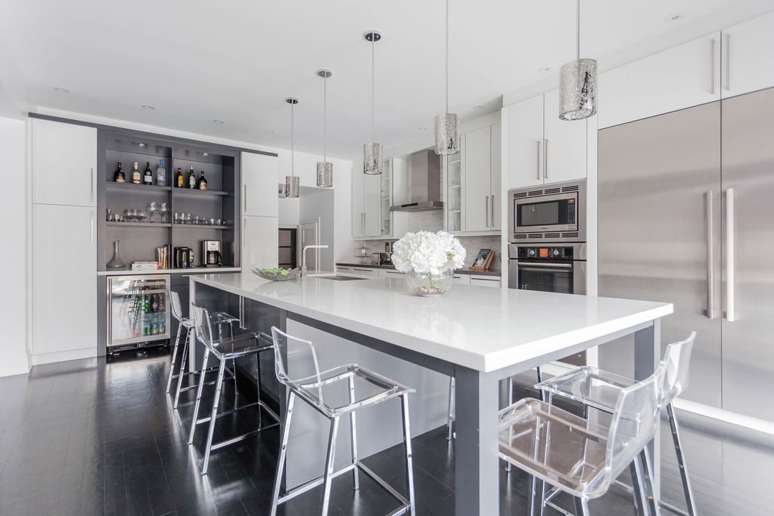 A kitchen with black cabinets and stools and a large island.