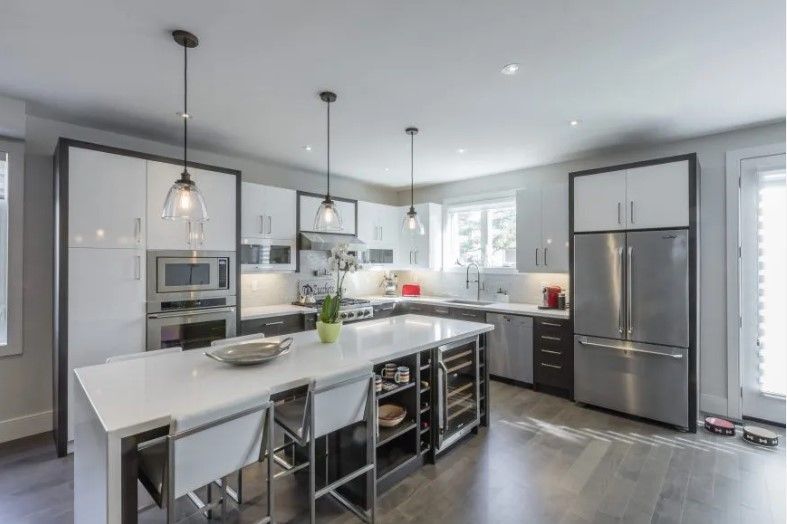 A kitchen with white cabinets and stainless steel appliances and a large island.