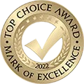 A gold top choice award mark of excellence stamp with a check mark in the center.