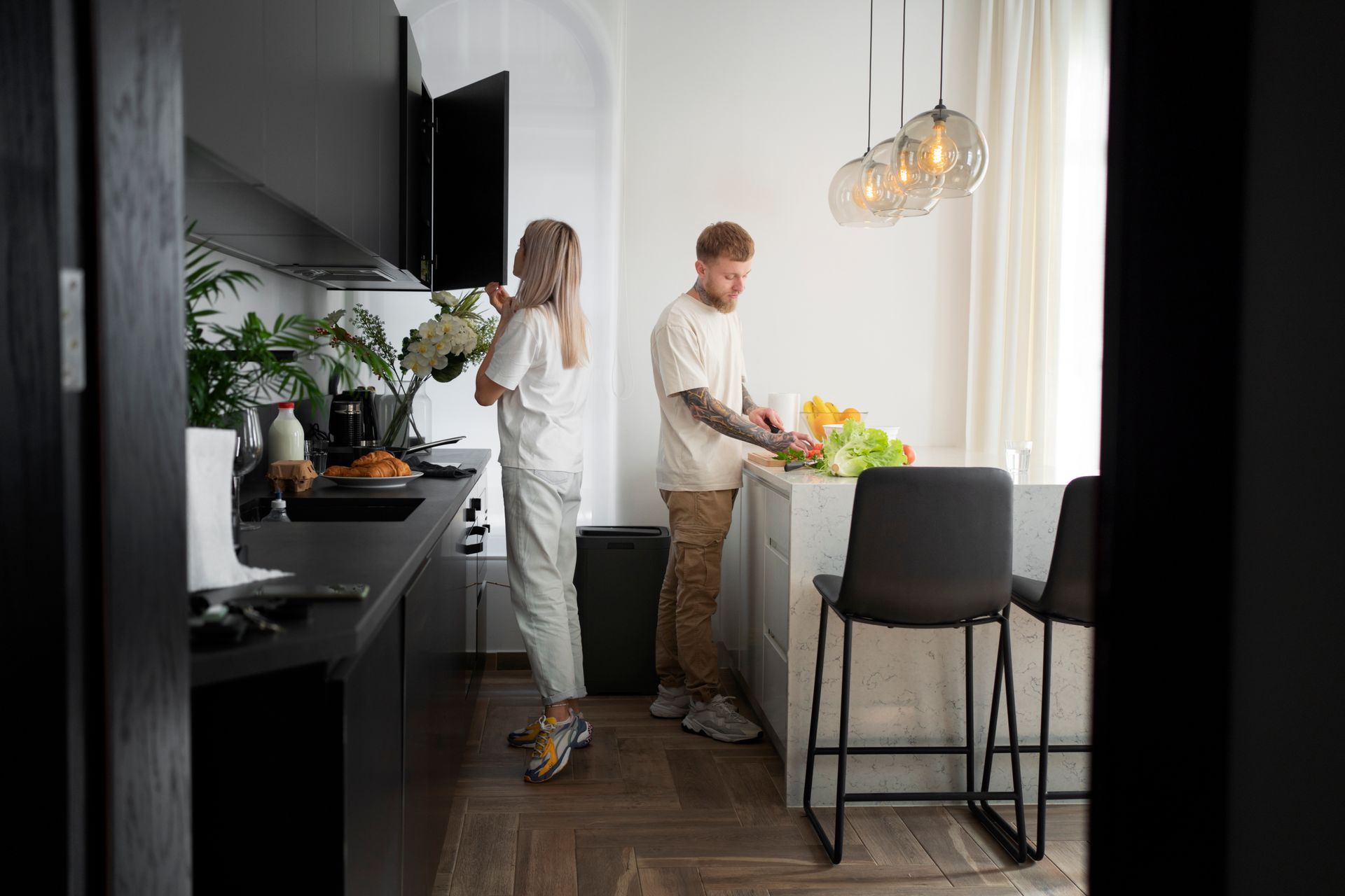 A man and a woman are standing in a kitchen preparing food.