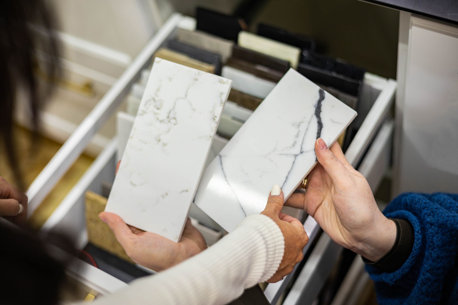 Two people are holding marble tiles in their hands in a store.