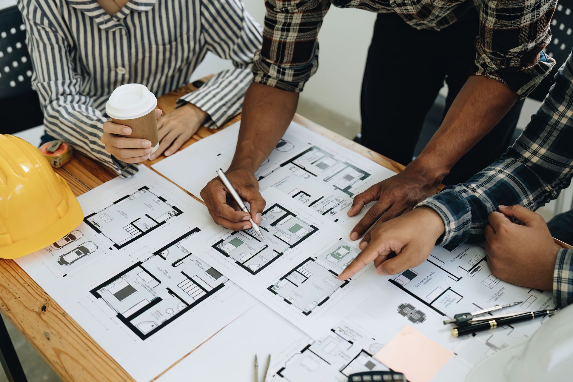 A group of people are sitting around a table looking at a blueprint.