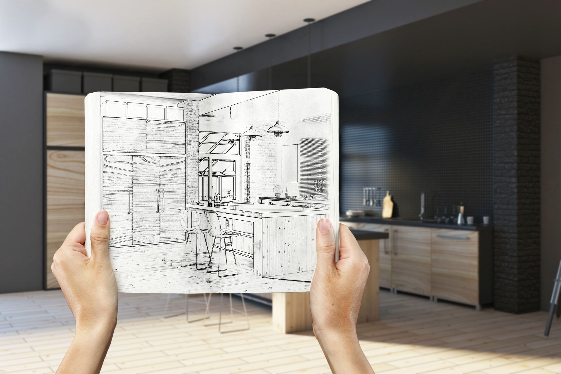 A person is holding a drawing of a kitchen in a notebook.