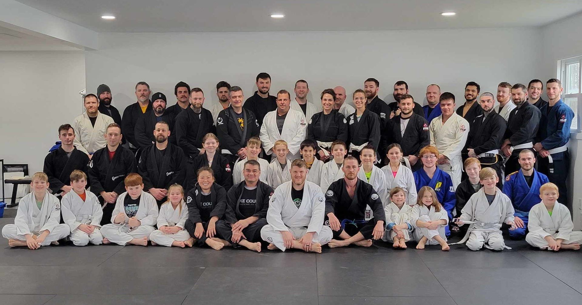 Group of people in martial arts uniforms posing together on a mat.