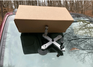 A cardboard box is sitting on top of a car windshield