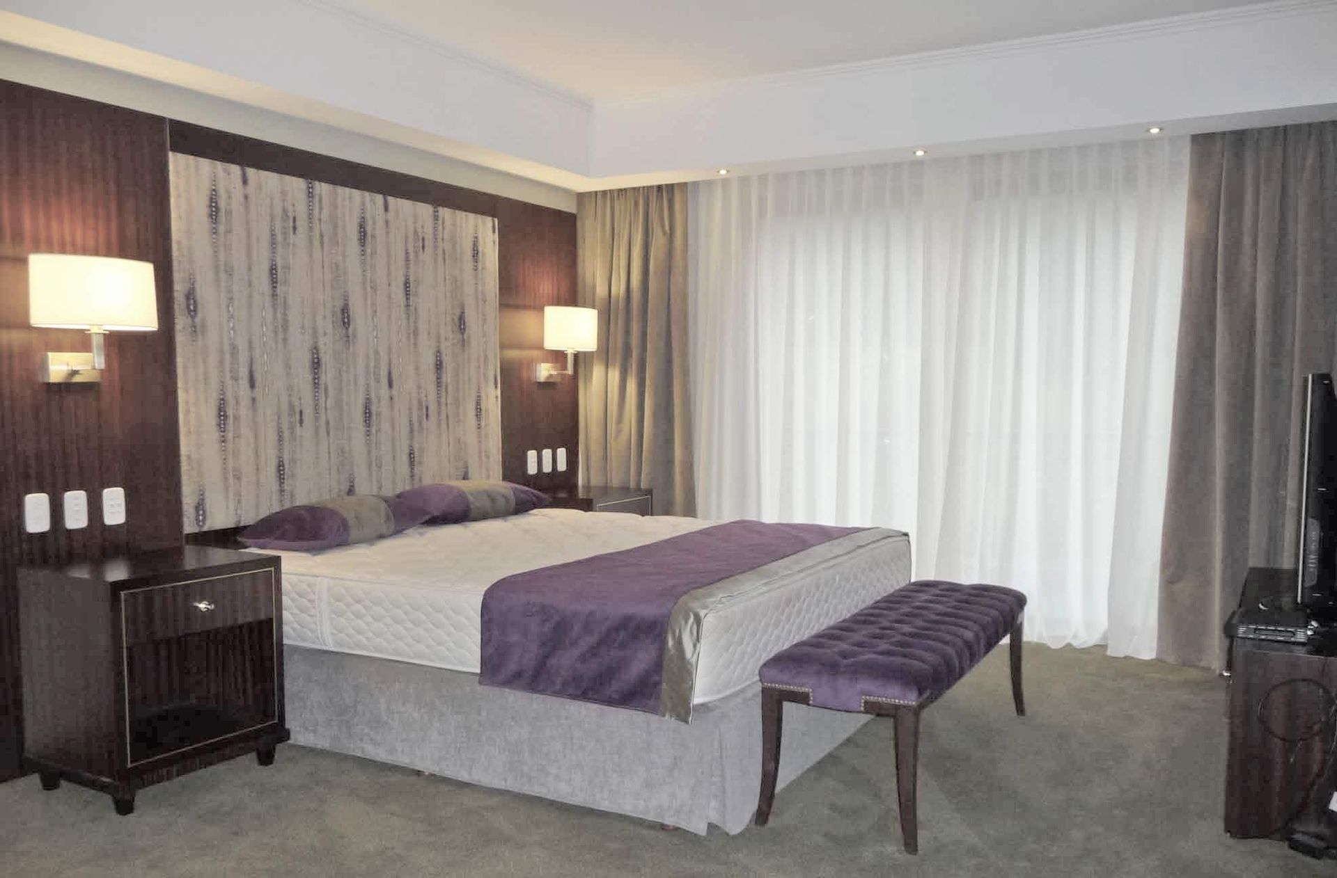 Una habitación de hotel con una cama grande y un banco.