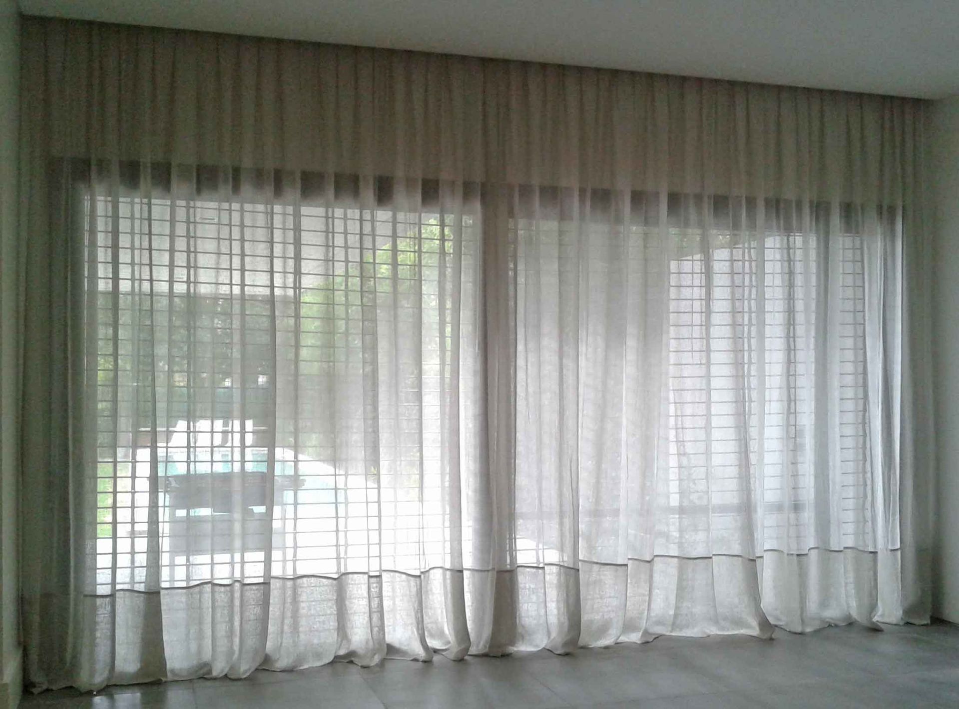 Una sala de estar con una gran ventana y cortinas blancas.