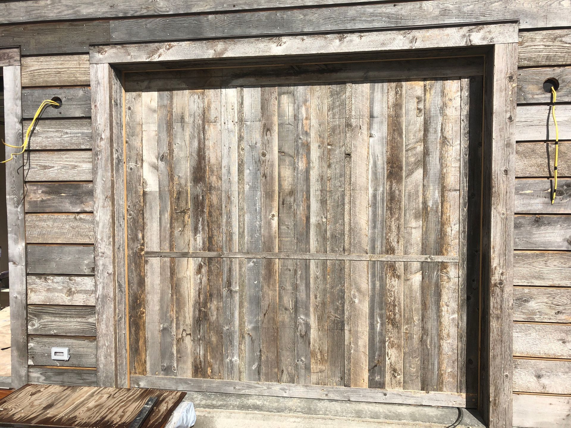 Wooden garage door made of weathered planks. Grey, brown, and tan hues.