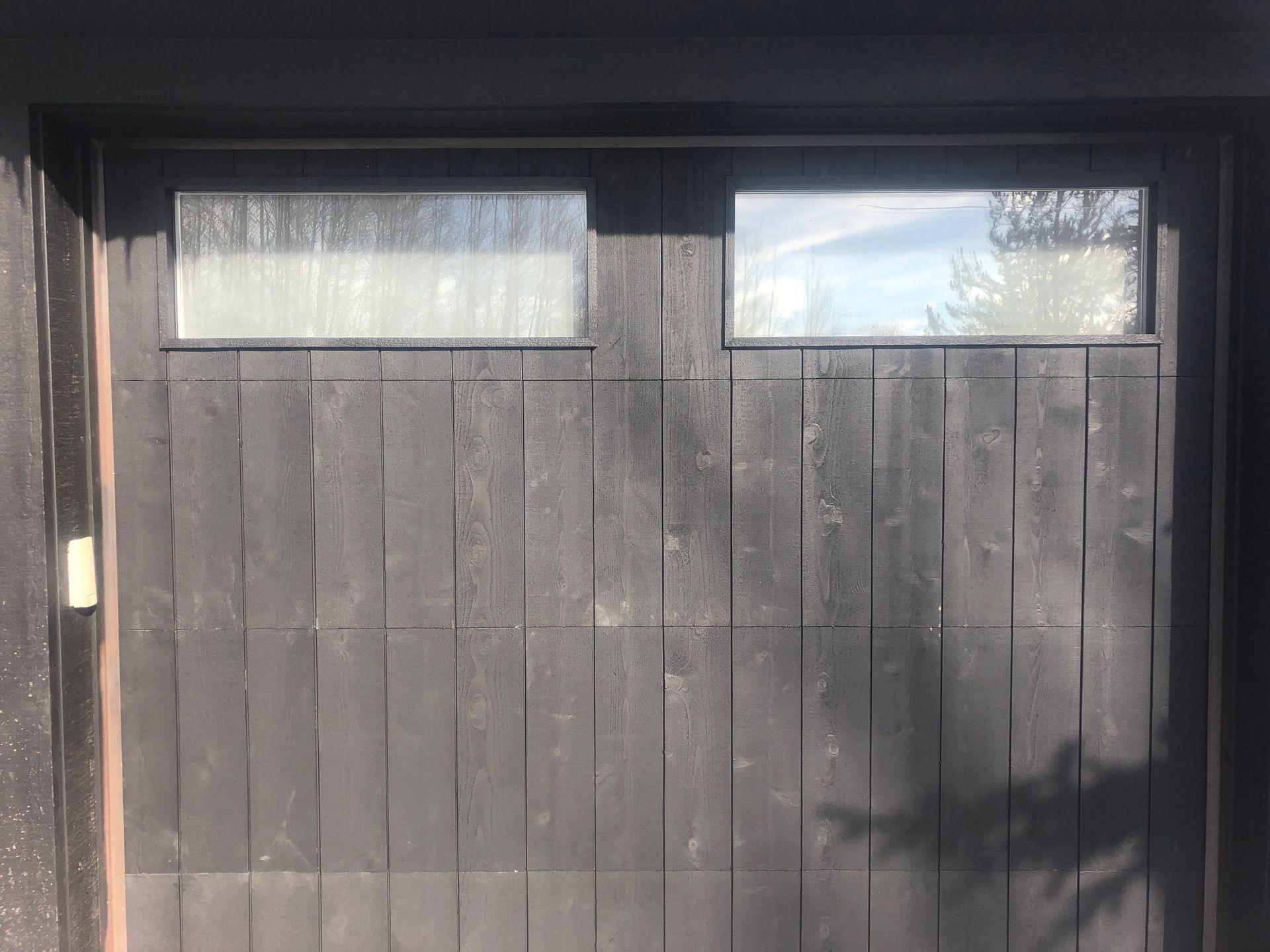 Dark wooden garage door with two rectangular windows at the top.