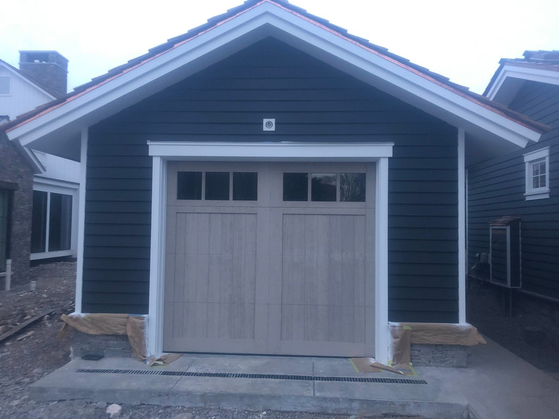 Dark blue garage with tan doors, white trim, and red roof trim.