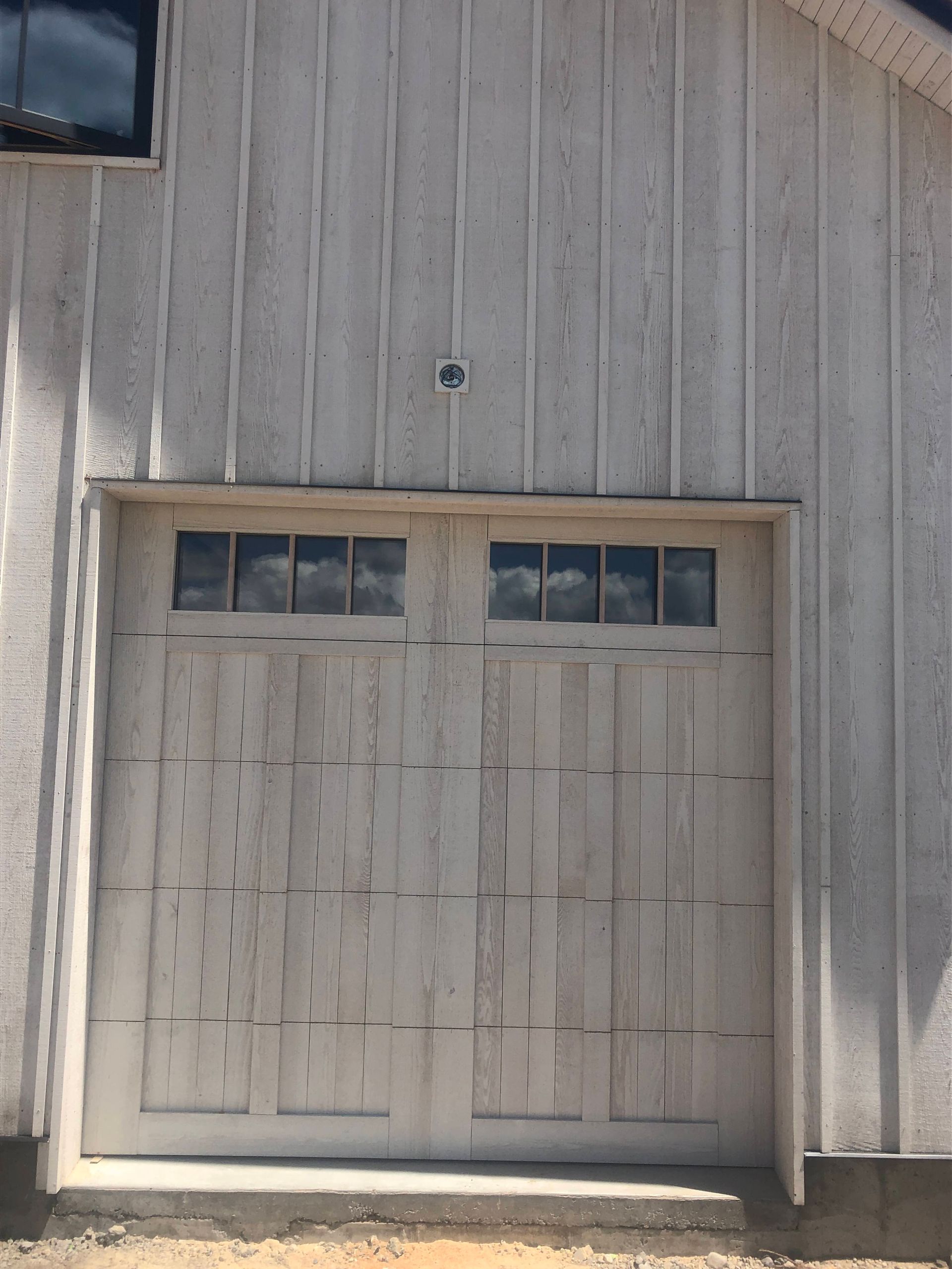 White garage door with windows, on a white clapboard building.