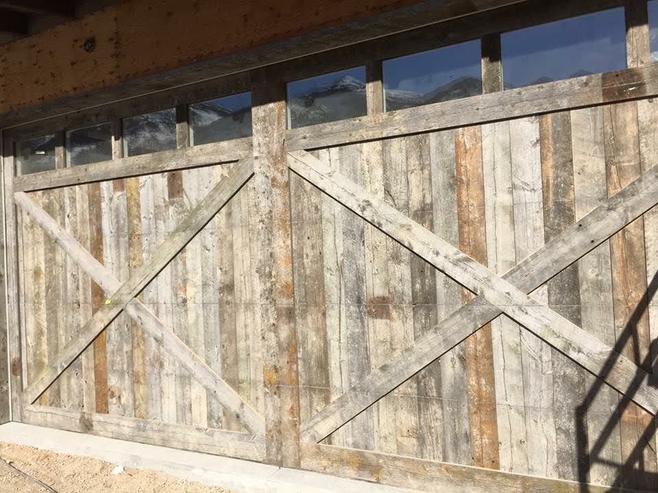 Rustic wooden garage door with diagonal cross bracing, windowed top.
