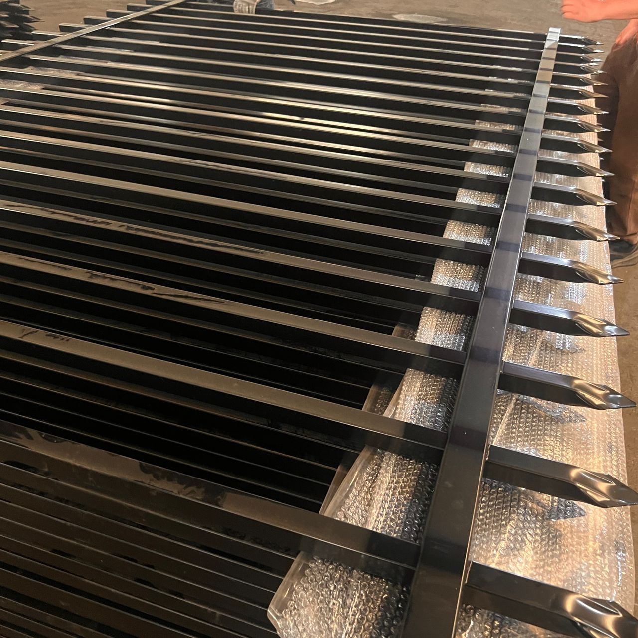 Black metal fence sections stacked, ready for installation.