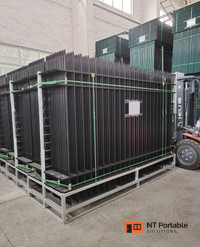 Black metal fence panels stacked on a pallet inside a warehouse, ready for shipping. A forklift is nearby.