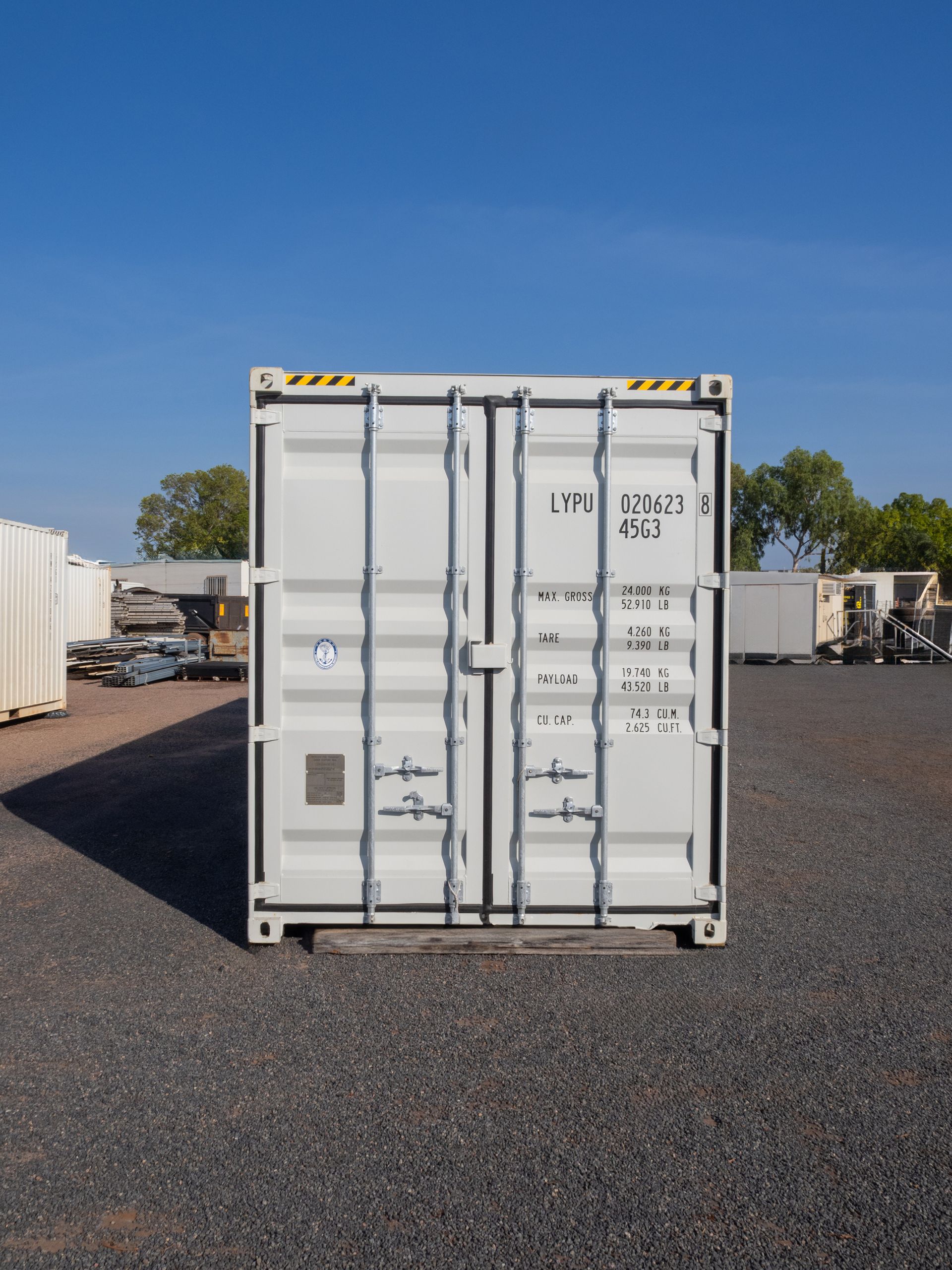 White cargo container on gravel, in a sunny outdoor lot.
