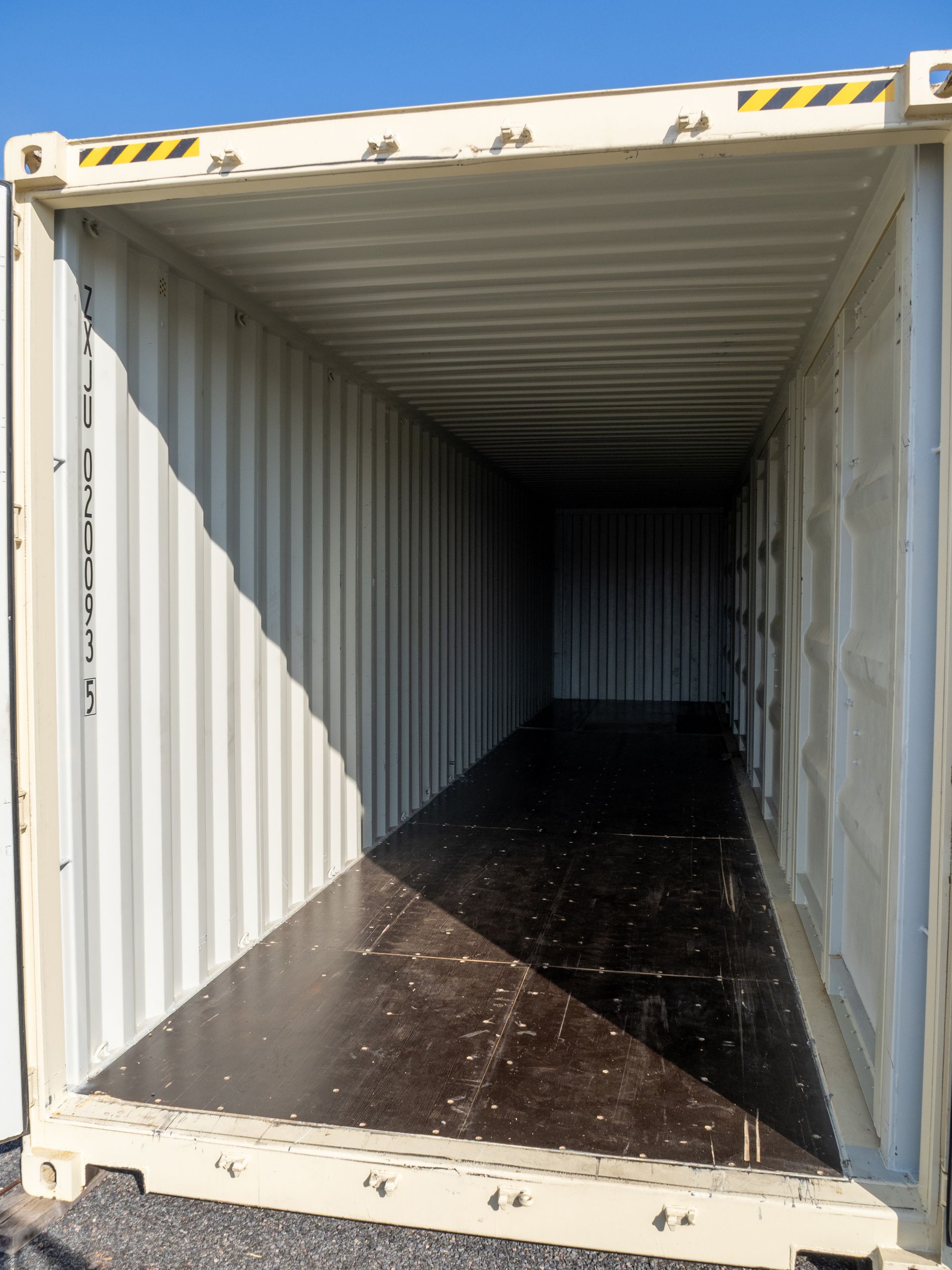 Inside of an empty beige shipping container; dark floor, corrugated walls.