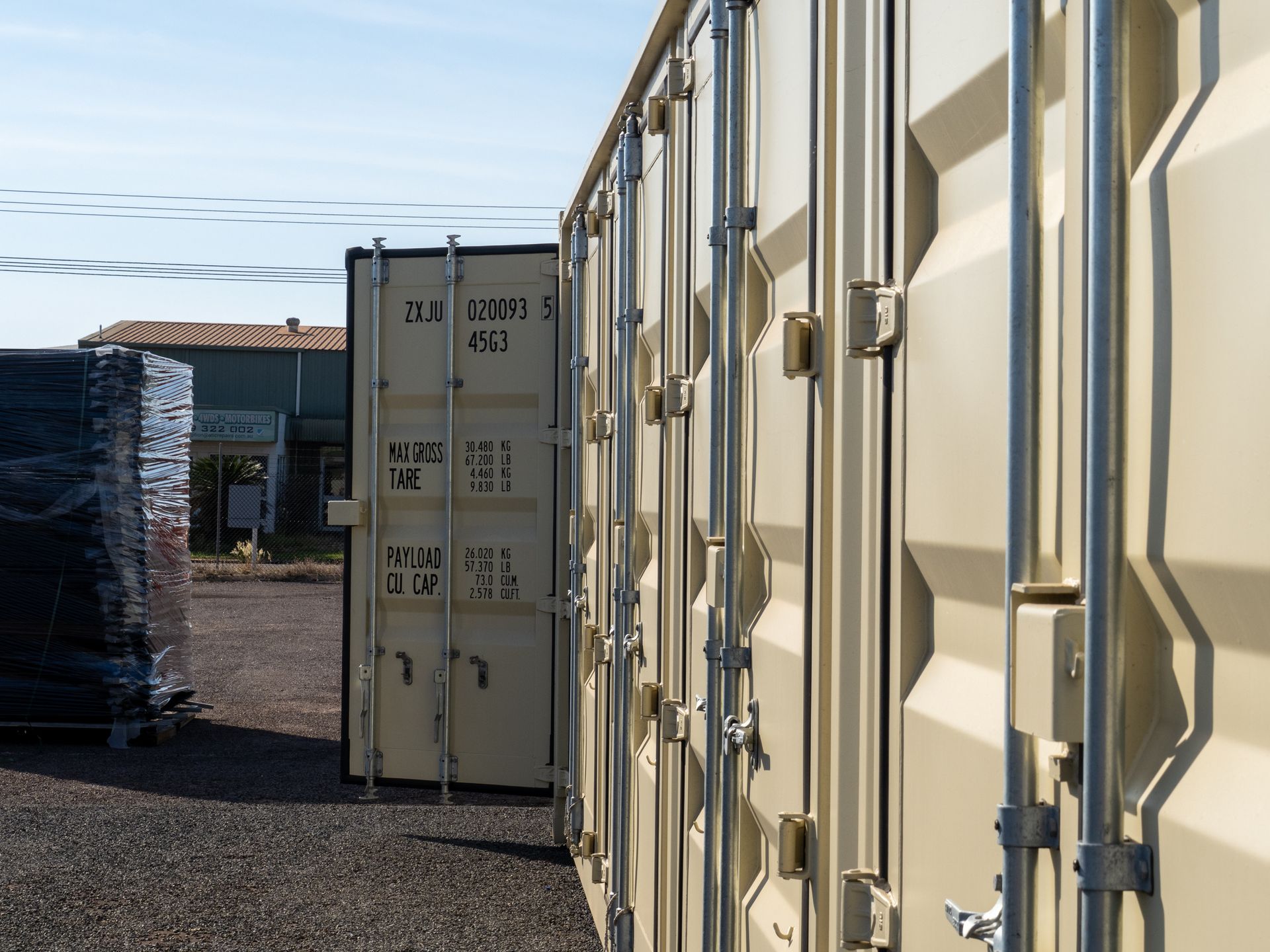 Beige storage containers, one open, arranged outdoors on gravel.