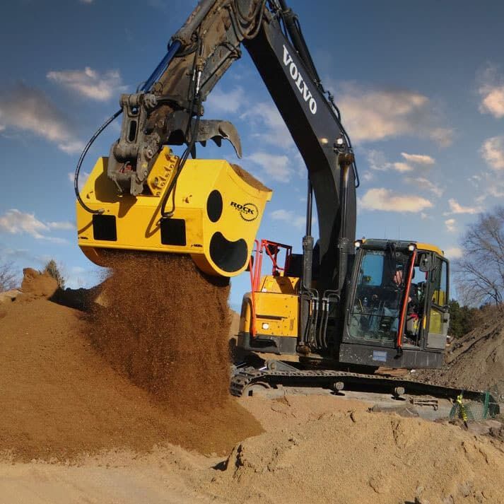 White Bobcat skid-steer loader with a soil compactor attachment on a construction site next to a home.