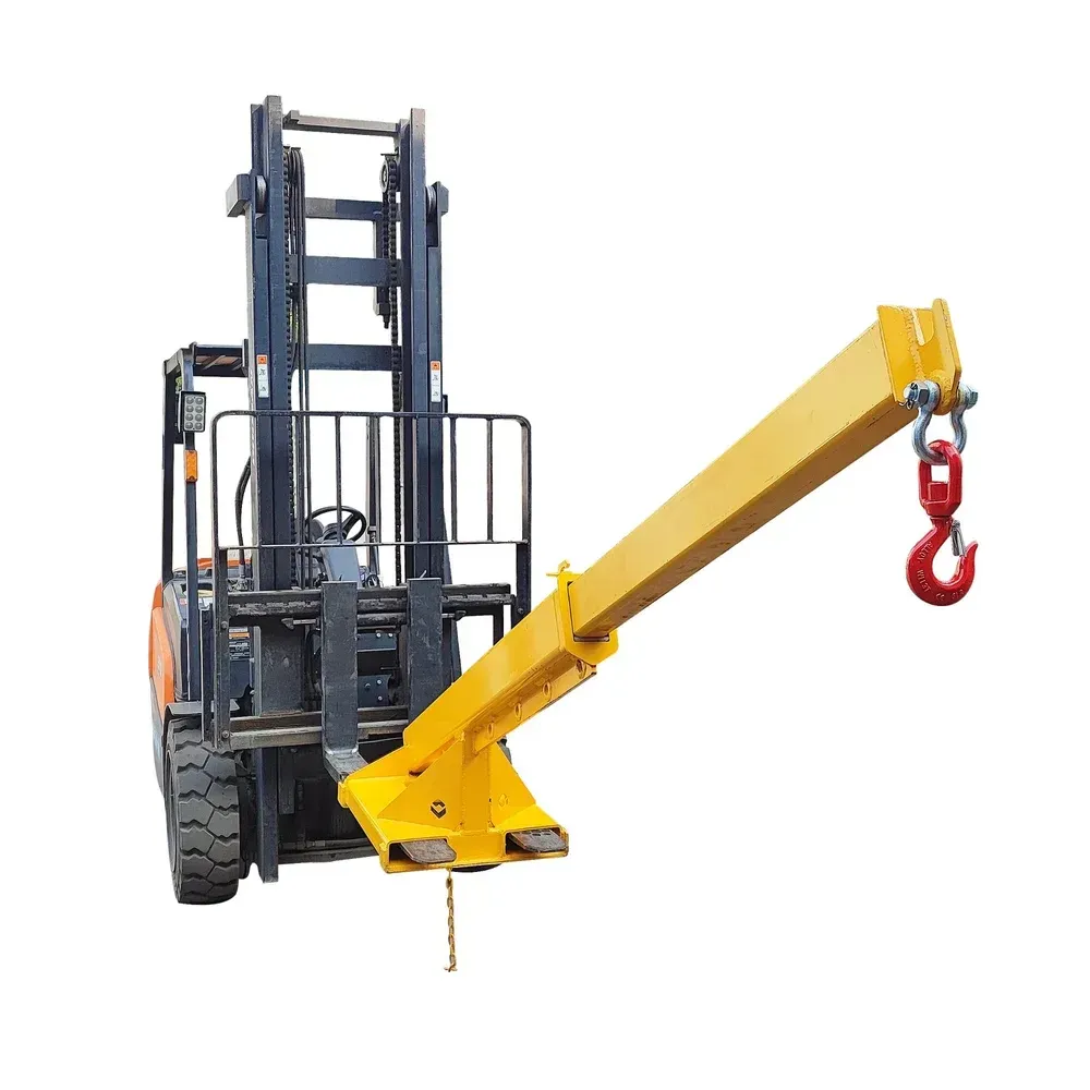 Yellow forklift attachment with a red lifting hook and two forks; outdoors.