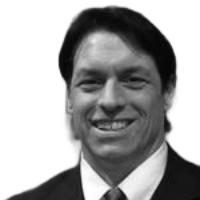 Man smiling, wearing a suit and tie, against a white background.