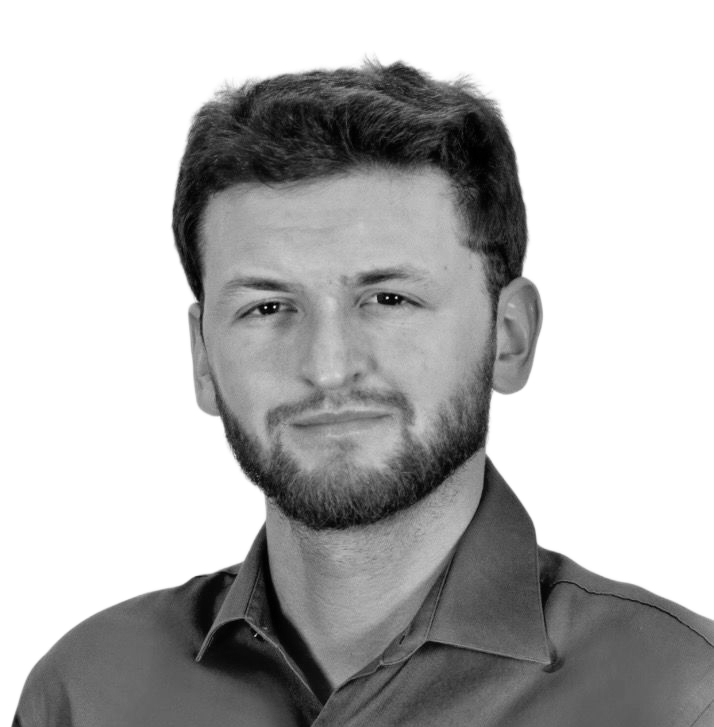 Man smiling, wearing a suit and tie, against a white background.