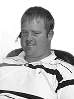 Man wearing a white and black polo shirt, sitting indoors, with a headset.