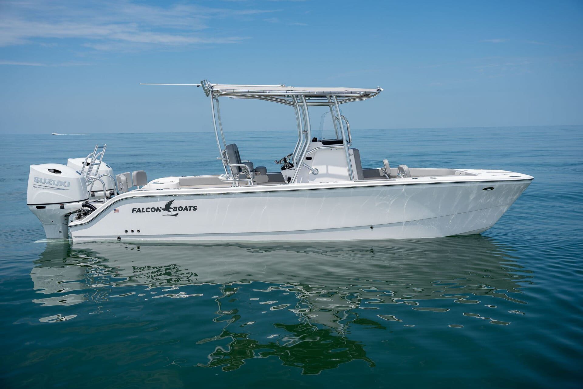 A boat with a black, gray, and teal wrap floats in shallow, clear water under a cloudy sky.