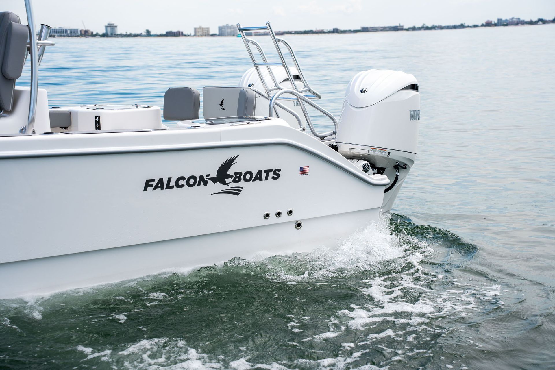 Interior of a boat cockpit with helm, seats, and controls. The boat is white with gray accents, and a calm body of water is in the background.