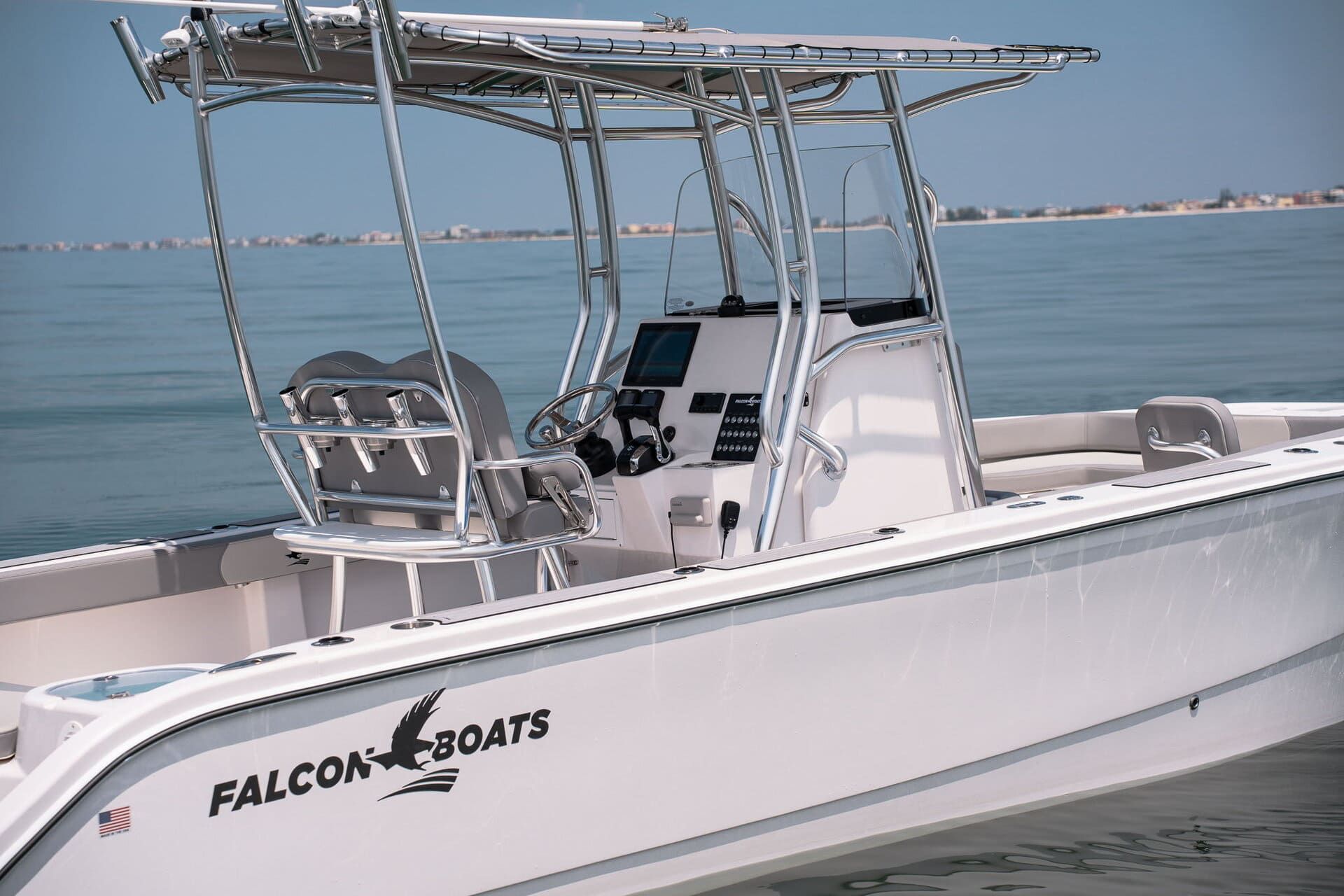 A white boat on a trailer has a black and blue abstract design on its side and is inside a building.