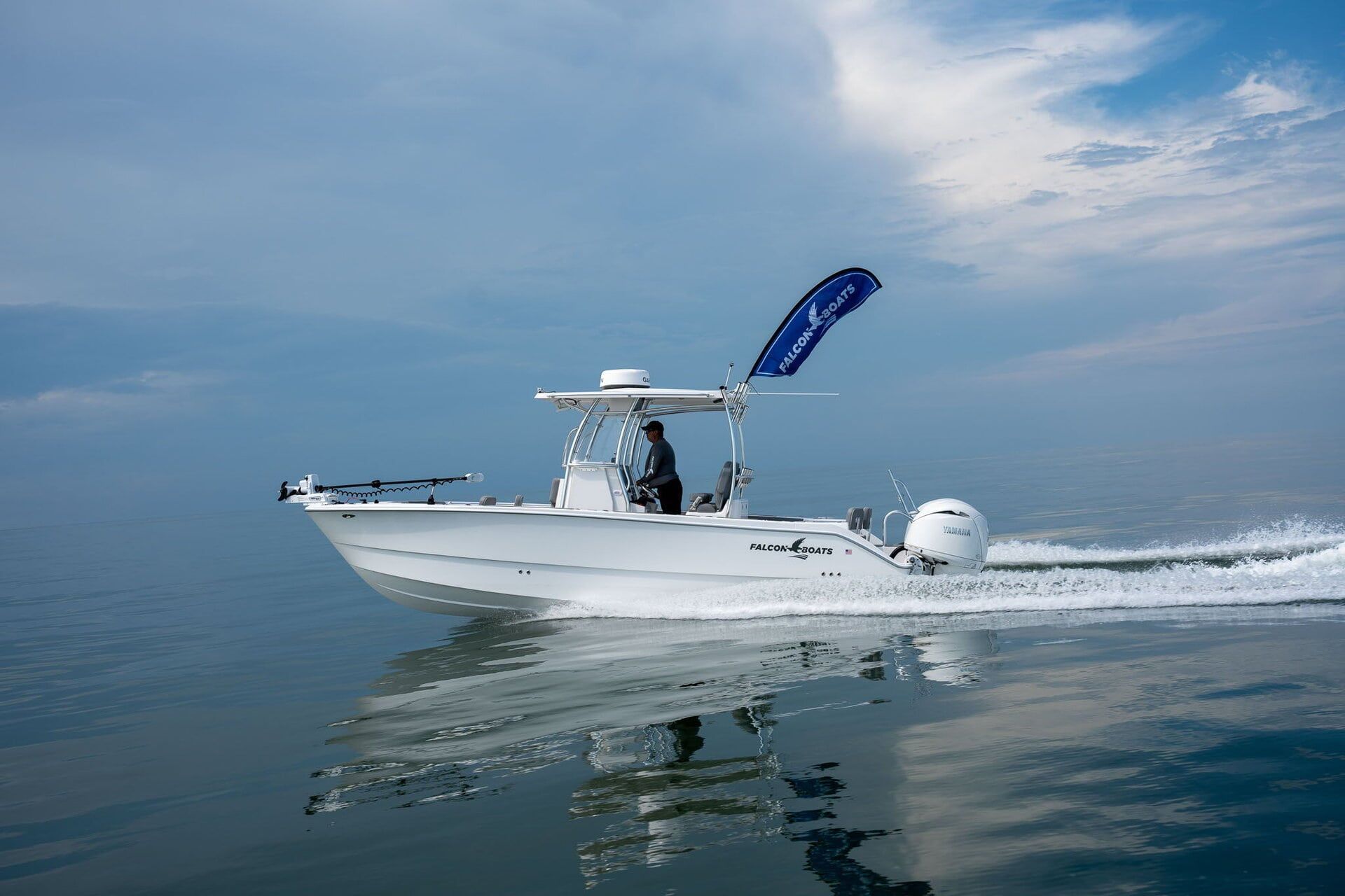 A white and blue fishing boat docked at a pier under a sunny sky. The boat has a shaded helm.
