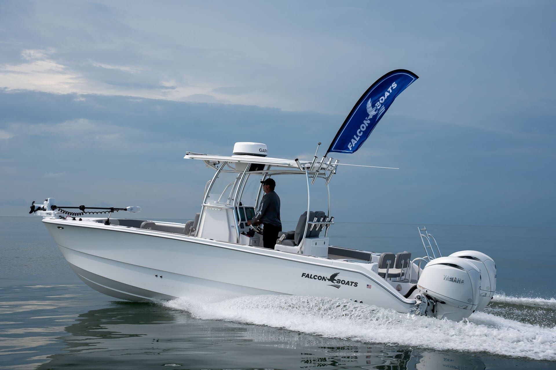 Blue and white motorboat docked at a marina on a sunny day. Other boats and docks are in the background.