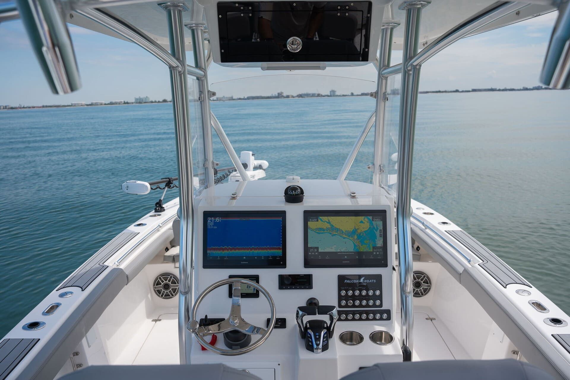 A white Falcon boat with two Suzuki outboard motors in calm blue water. The boat has gray accents and a ladder.