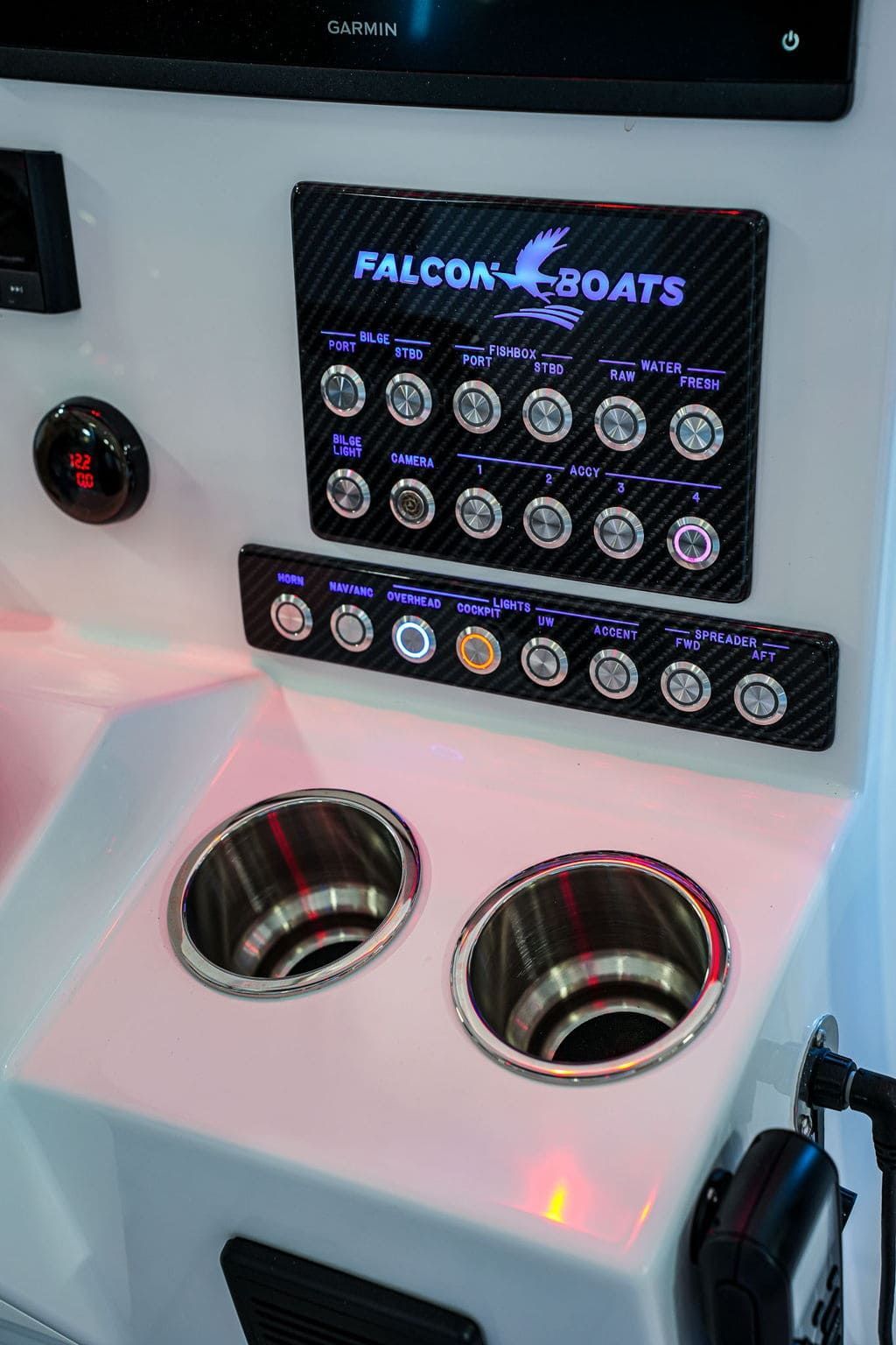 Dashboard of a teal and white boat with gauges, switches, and steering wheel, against a backdrop of ocean and sky.