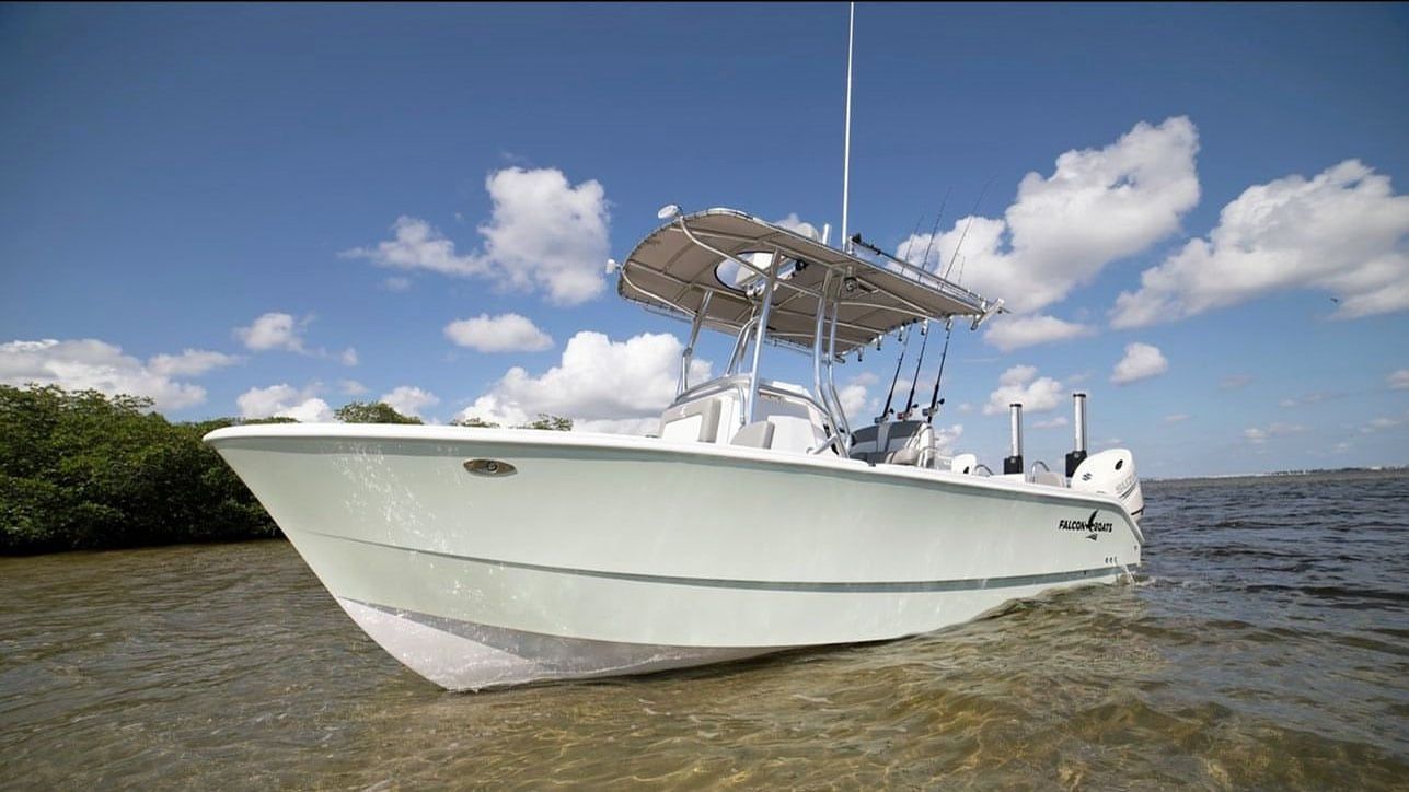 Light green motorboat in shallow water, under a blue sky with some clouds.